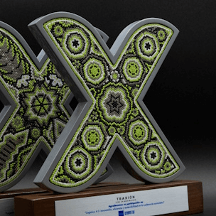 Logo de Traxión enchaquirado sobre base de madera con placa de metal