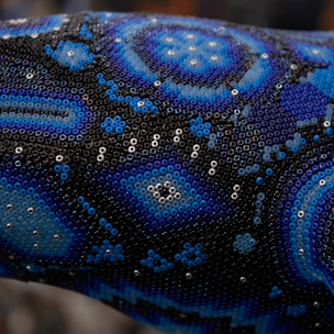 Escultura de ballena jorobada color azul sobre base color café cubierta con chaquiras