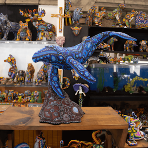 Escultura de ballena jorobada color azul sobre base color café cubierta con chaquiras