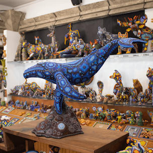 Escultura de ballena jorobada color azul sobre base color café cubierta con chaquiras