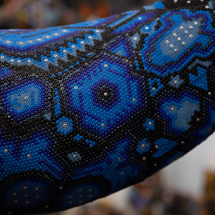 Escultura de ballena jorobada color azul sobre base color café cubierta con chaquiras