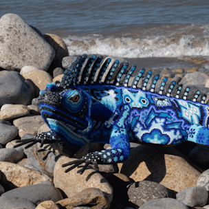 Escultura de forma de iguana cubierta con chaquira de colores azul y blanco