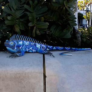Escultura de forma de iguana cubierta con chaquira de colores azul y blanco