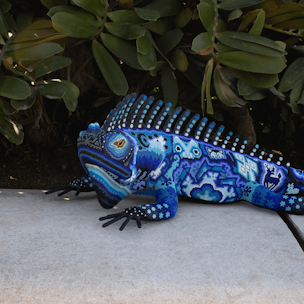 Escultura de forma de iguana cubierta con chaquira de colores azul y blanco